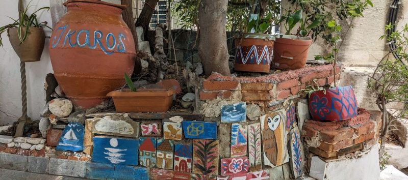 Peinture sur pavé et pot de terre dans une rue à Ikaria